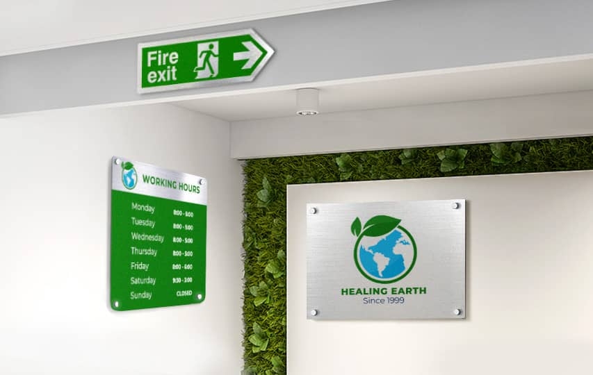 Green fire exit sign with arrow, working hours schedule, and Healing Earth logo on office wall